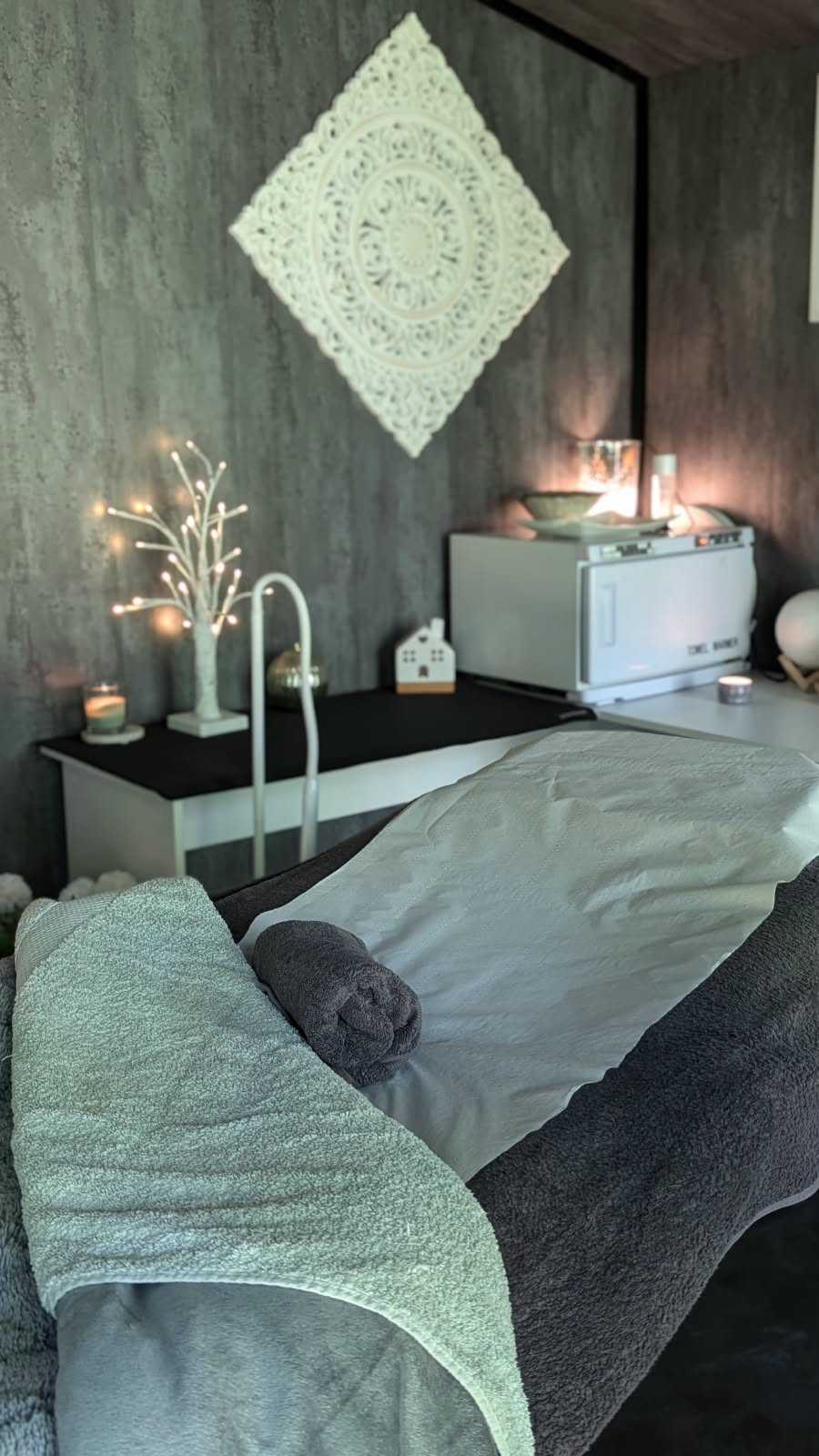 Treatment bed dressed with warm towels, ready for a facial or massage in the woodland room